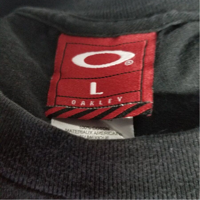 Red woven Oakley tag with white O ellipse logo, size L, OAKLEY underneath, with a French-English care label