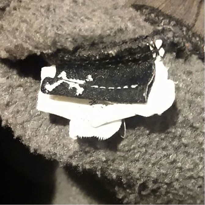 Black woven Oakley tag with white embroidery, photographed at an angle in low light